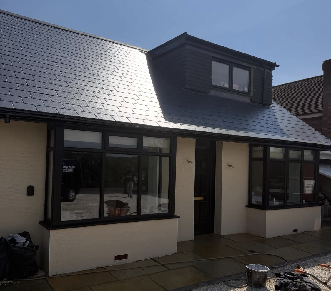 After: crisp white render with a new slate roof and dormer