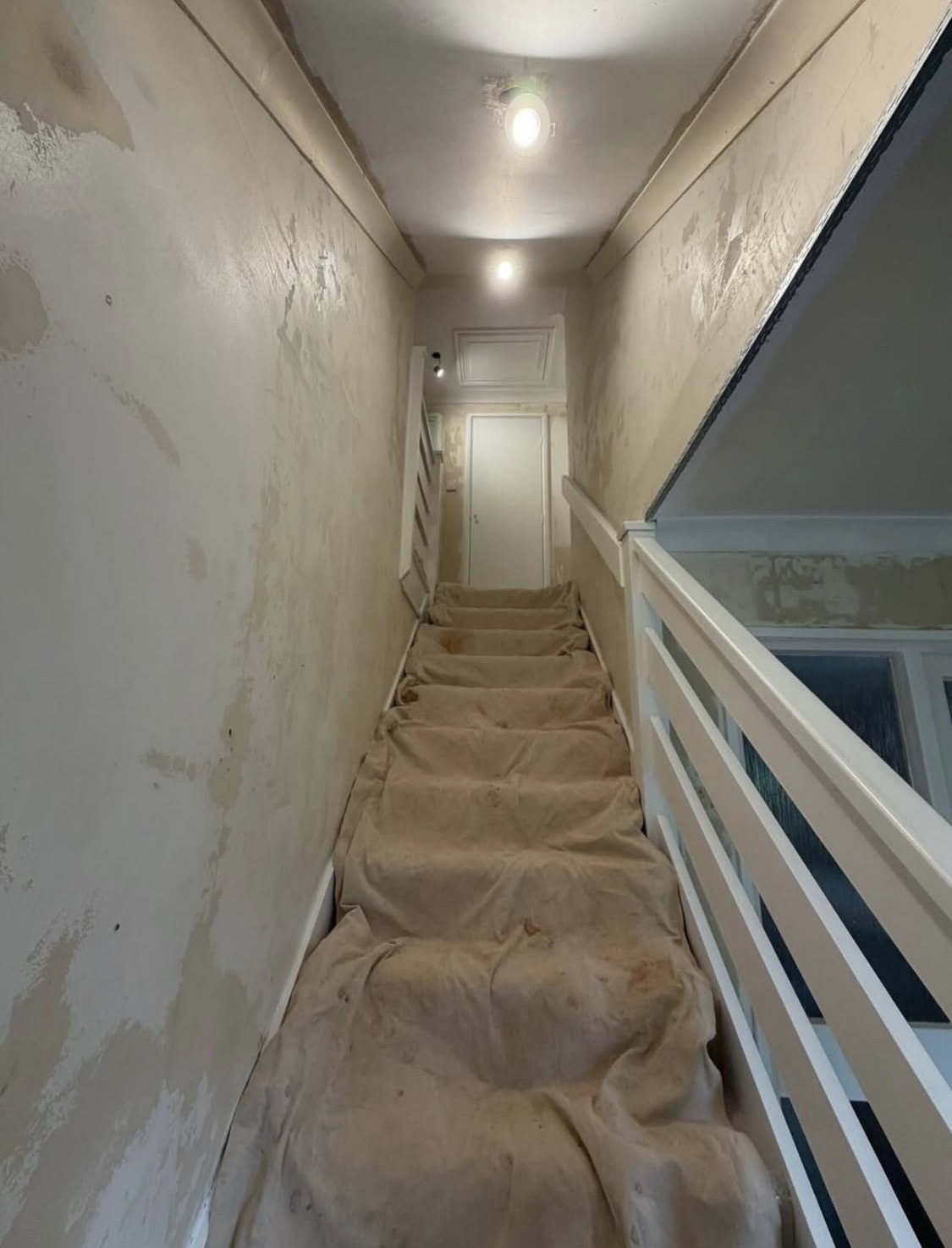 Before: hallway walls stripped back and prepared for fresh plaster
